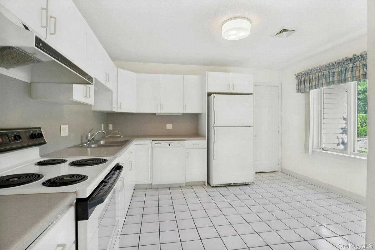 Tiled kitchen floor with window overlooking the front and door to garage..