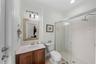 Full bathroom with glass-enclosed shower and vanity storage.