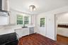 Kitchen featuring wall chimney exhaust hood, dark wood-style flooring, white cabinetry, crown molding, and stainless steel dishwasher