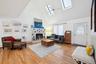 Living room with a healthy amount of sunlight, a tiled fireplace, high vaulted ceiling, and a skylight
