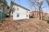 Large open and airy fenced-un yard with view of the rear of the house showing both levels.