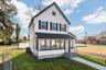 View of front of home with a sunroom and a shingled roof