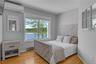 Bedroom featuring a wall unit AC, multiple windows, and baseboard heating