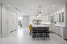 Kitchen with ornamental molding, a breakfast bar area, light countertops, white cabinets, and an island with sink