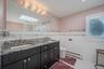Bathroom with a skylight, baseboard heating, double vanity, a stall shower, and tile walls