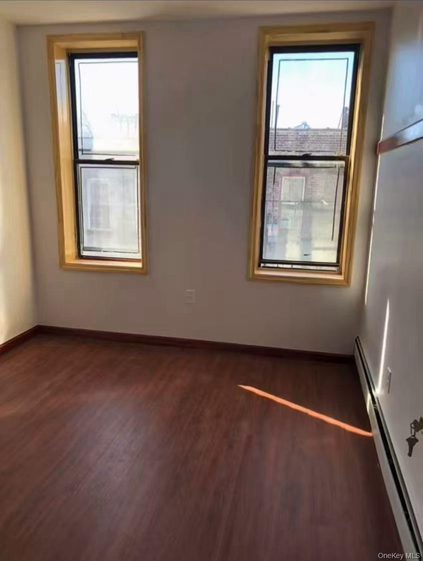 Empty room with a baseboard radiator and dark wood finished floors
