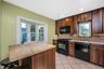 Kitchen featuring wood-finish cabinetry, black appliances, tile flooring, and a bay window