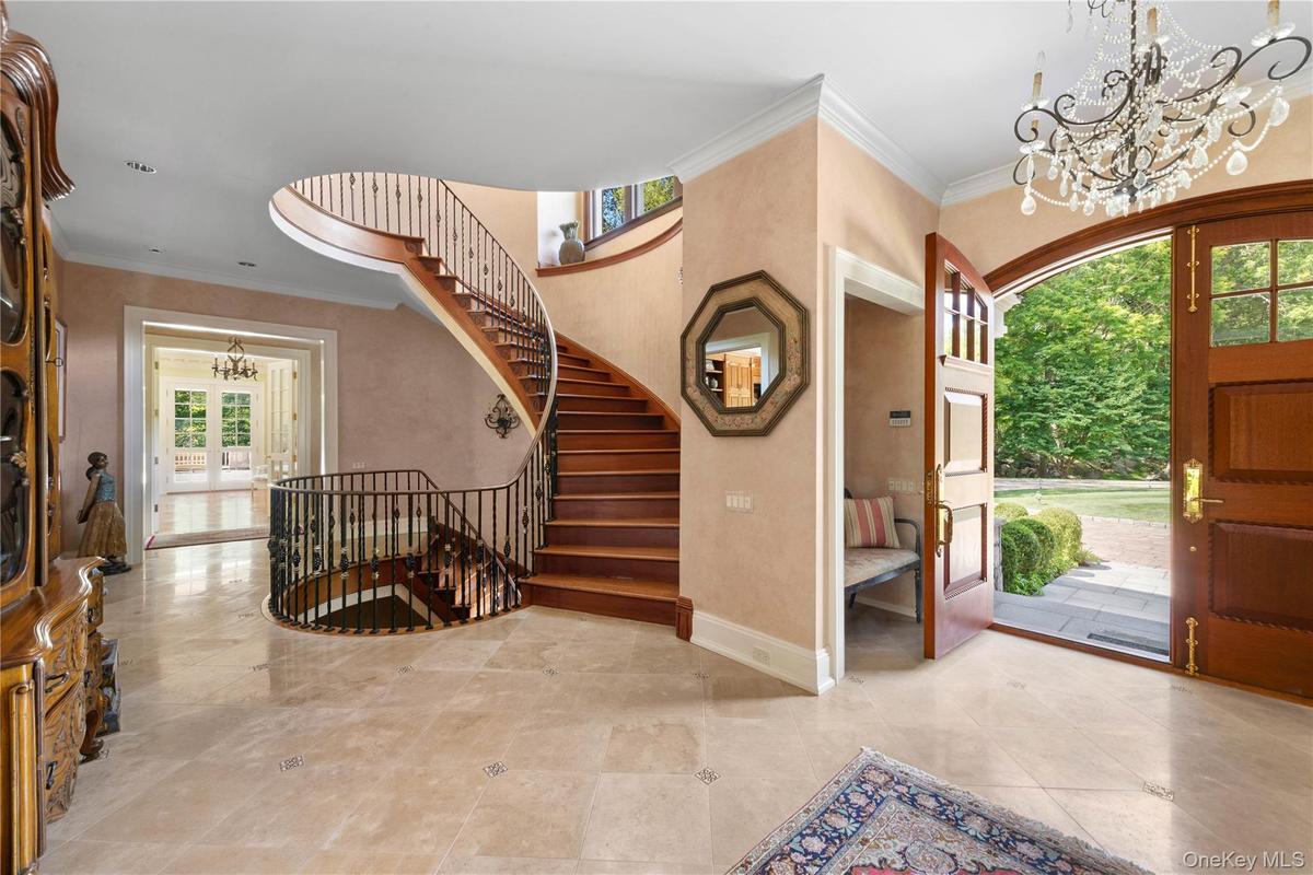 Entryway featuring a chandelier, ornamental molding, french doors, and stairway