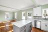 Kitchen featuring white cabinetry, stainless steel dishwasher, light stone counters, gray cabinetry, and crown molding