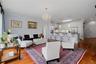 Another view of the living room emphasizing the open layout, beautiful chandelier, and primary suite entrance.