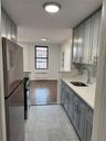 Kitchen with a sink, radiator, gray cabinets, fridge, and range