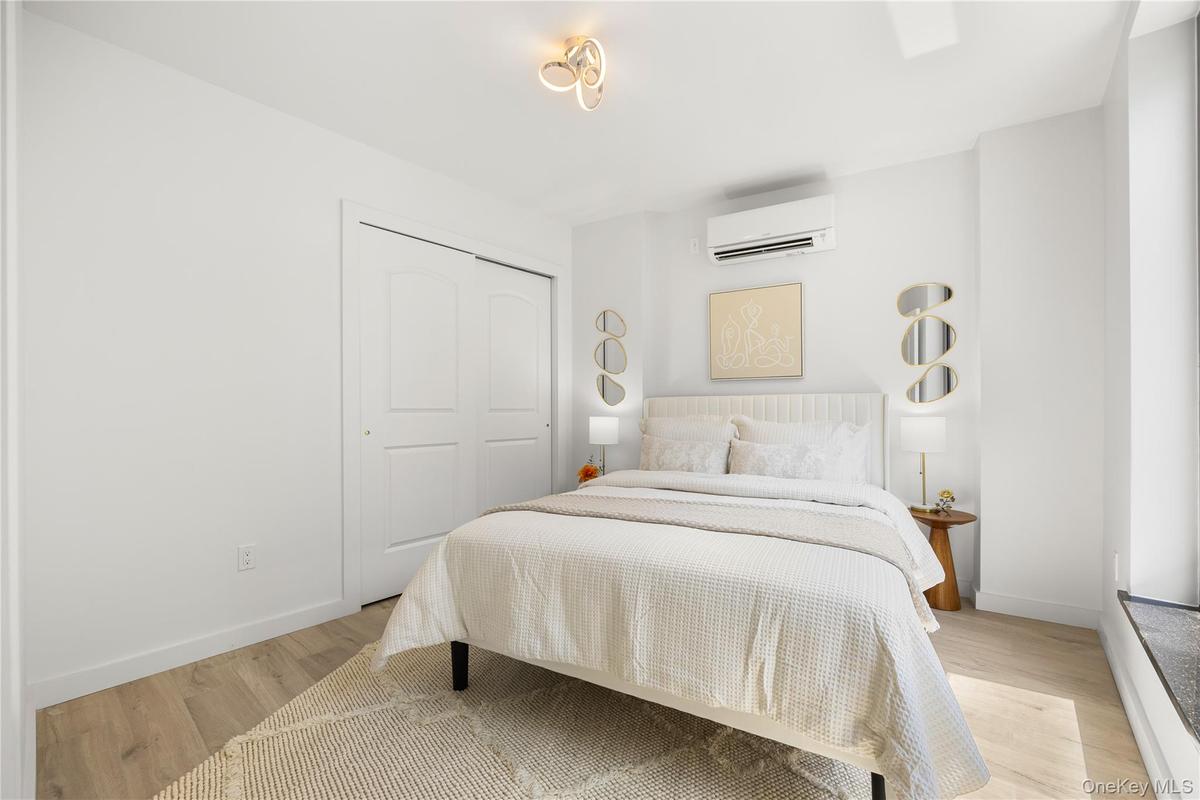 Bedroom featuring baseboards, a wall mounted air conditioner, a closet, and light wood finished floors