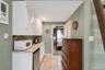 Galley area featuring white shaker-style cabinetry with louvered doors, a mosaic tile backsplash, and a granite-finish countertop