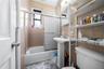Bathroom featuring enclosed tub / shower combo and tile walls