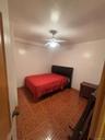 Bedroom with a textured ceiling, a ceiling fan, and light floors