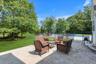 Paved stone patio with a fenced swimming pool, expansive lawn, and mature trees