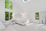 Bedroom with multiple windows, wood finished floors, high vaulted ceiling, and a skylight