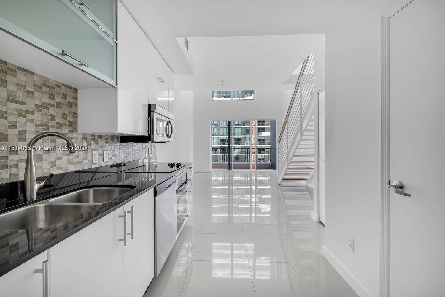 Welcome to Loft living at Infinity at Brickell for this spacious double high ceiling unit with modern white tile, gallery kitchen, half bathroom downstairs, floor to ceiling windows open loft ...