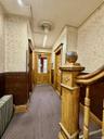 Corridor featuring wallpapered walls, radiator heating unit, wainscoting, and carpet floors