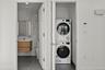 Laundry room with stacked washing machine and dryer, tile walls, and tile patterned flooring