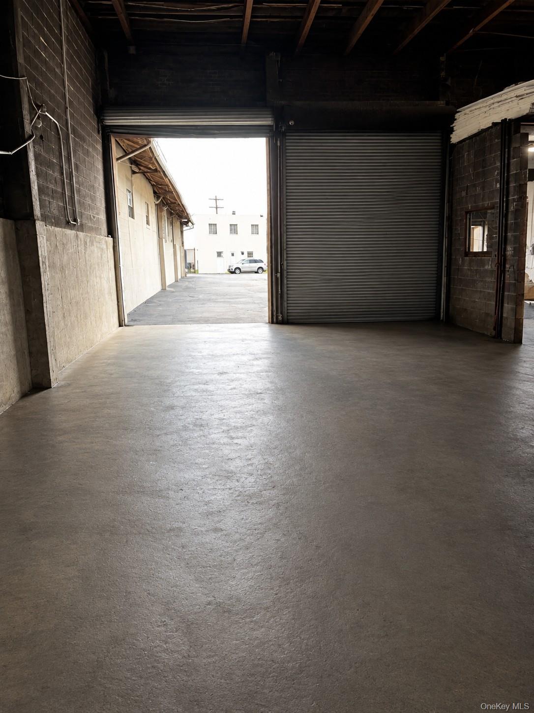 Polished concrete flooring, exposed wood beam ceiling, concrete block walls, and a large roll-up door