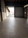 Polished concrete flooring, exposed wood beam ceiling, concrete block walls, and a large roll-up door