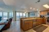 This open kitchen boasts granite countertops, stainless steel appliances, and a breakfast bar overlooking the ocean-facing dining space—perfect for en