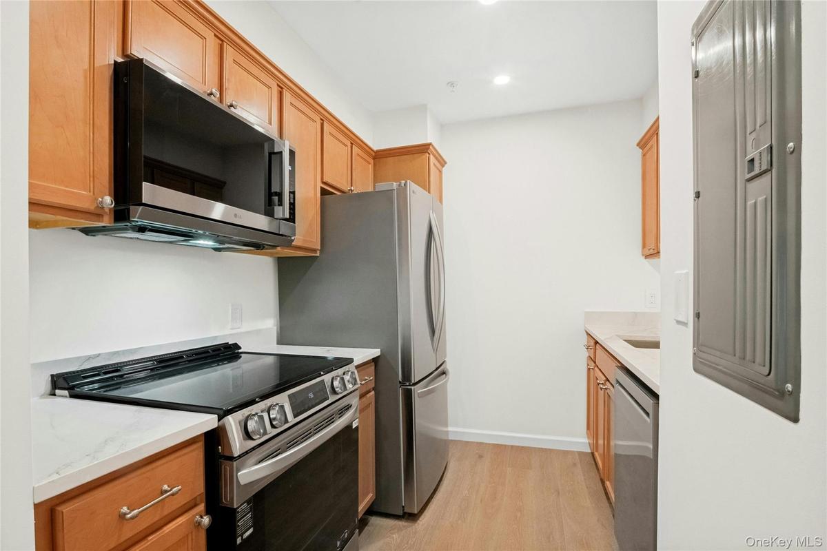 Alternative view of kitchen with all new stainless steel LG appliances, white quartz countertops, and brushed metal hardware