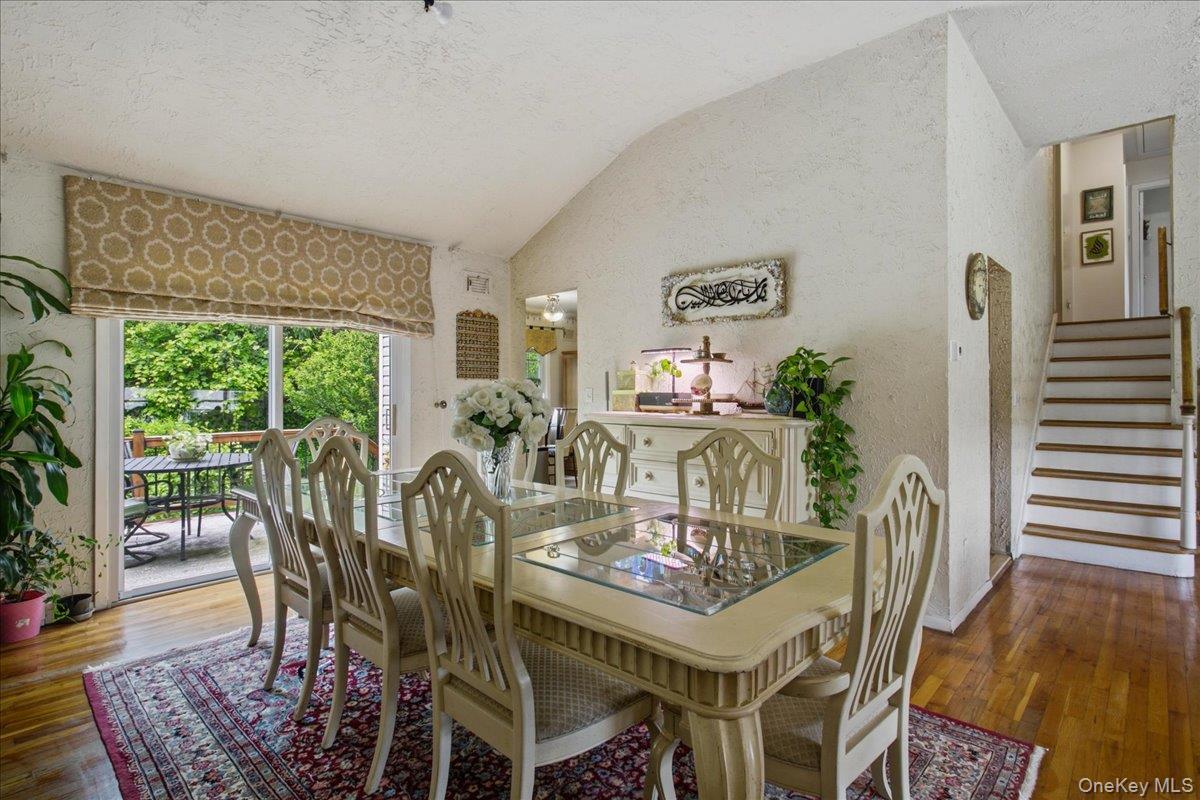 Dining area with vaulted ceiling and wood-finish flooring