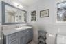 Bathroom featuring tile walls, visible vents, toilet, vanity, and wainscoting