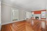 Sunlight, original wood floors, and a brick fireplace create a living room that feels warm, inviting, and unmistakably historic.