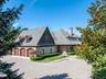 View of front facade with decorative driveway, brick siding, a garage, a chimney, and a patio area