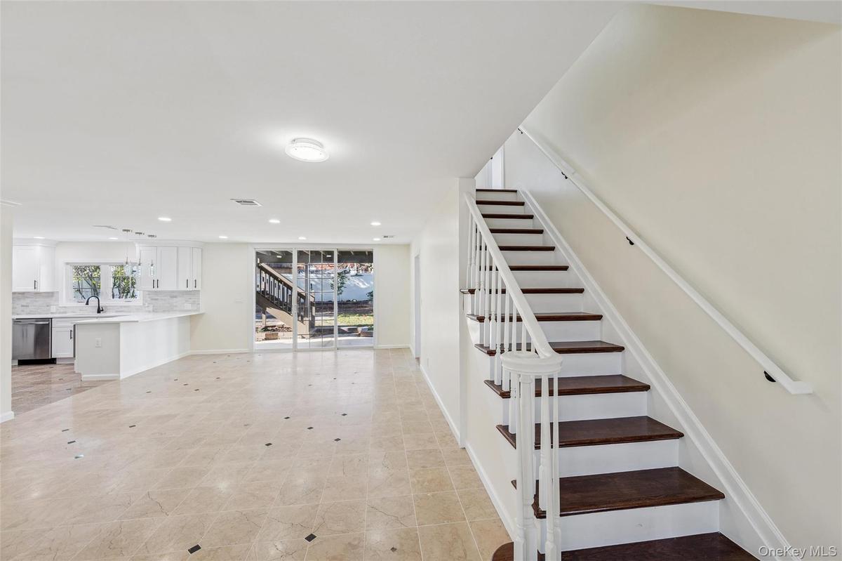 Tiled flooring with dark accent inlays, a white staircase with dark wood-finish treads, and recessed lighting