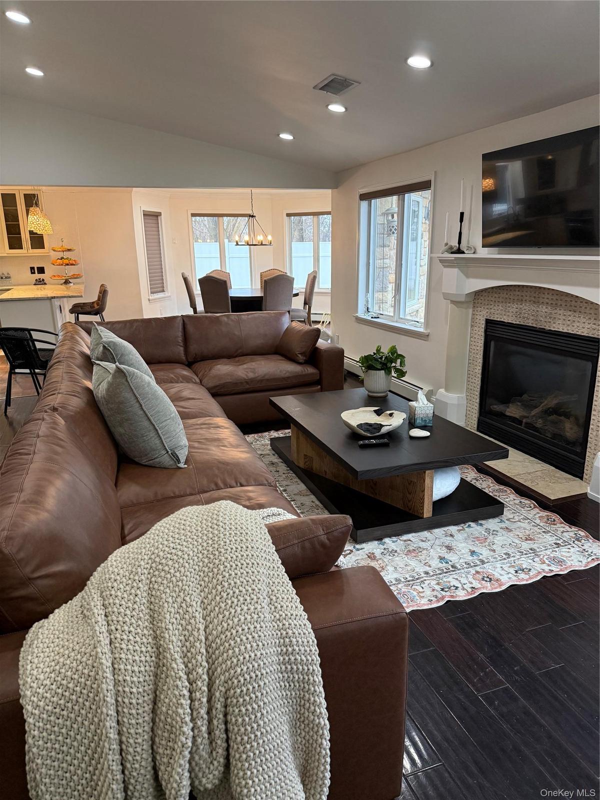 Living area featuring visible vents, wood finished floors, recessed lighting, a fireplace, and lofted ceiling