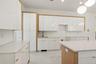 Kitchen featuring white cabinets, light stone countertops, light marble finish flooring, and hanging light fixtures