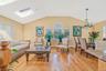 Living room with lofted ceiling, light wood finished floors, a skylight, and a chandelier