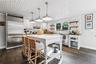 Kitchen with open shelves, appliances with stainless steel finishes, hanging light fixtures, and wine cooler