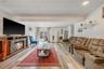 Living room with a glass covered fireplace, light wood-style flooring, and suspended lighting