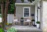 Front entryway with a paver patio, brick facade, stone accents, and a white vinyl fence