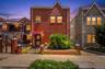 Brick exterior with a peaked roofline, front entry awning, decorative wrought iron security door, and a brick-capped privacy wall