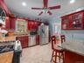 Kitchen featuring reddish brown cabinets, backsplash, appliances with stainless steel finishes, ornamental molding, and a ceiling fan