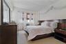 Bedroom featuring a wide headboard, twin nightstands, and a dresser with an integrated mirror