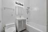 Modern bathroom featuring a white porcelain toilet, a vanity with a white basin and chrome faucet, and a medicine cabinet with mirrored doors