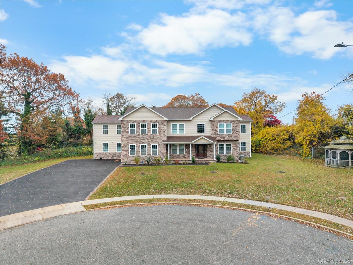 Traditional home with a porch, asphalt driveway, stone siding, and a front lawn