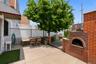 Outdoor patio featuring a built-in brick oven, concrete slab flooring, and a privacy fence with lattice detailing