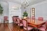 Dining area with a decorative wall, a wainscoted wall, a high end fireplace, crown molding, and dark wood-style flooring