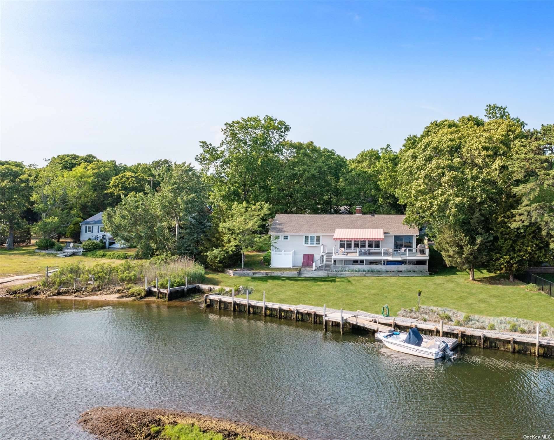 Waterfront ranch on James Creek with dock and large waterfront deck with shade awning.