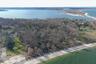 Aerial view of property's location featuring a nearby body of water and a forest