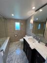 Spa-inspired primary bathroom featuring a walk-in shower with subway tile surround, marble-finish flooring, and a double vanity with quartz countertop