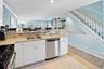 Kitchen featuring light stone counters, light tile patterned floors, a sink, crown molding, and appliances with stainless steel finishes